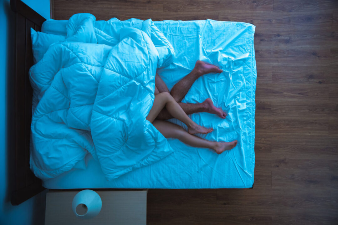 The man and a woman laying under a duvet. evening night time. view from above The man and a woman laying under a duvet. evening night time. view from above