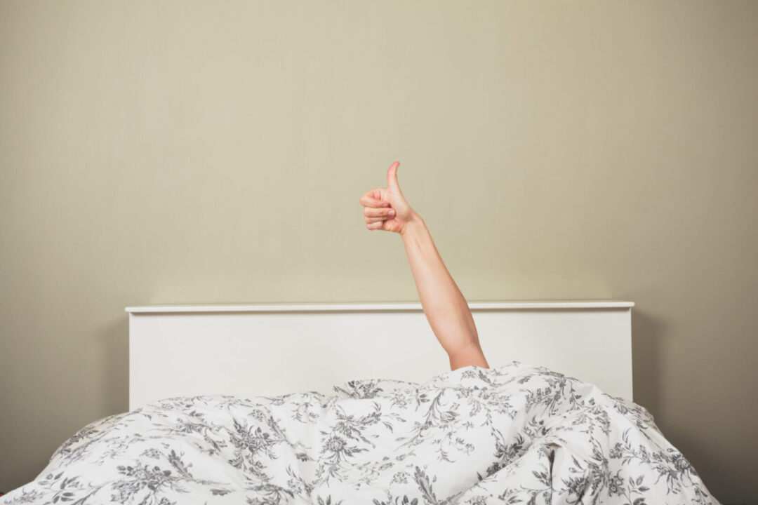 Woman in bed giving thumbs up Affordable services